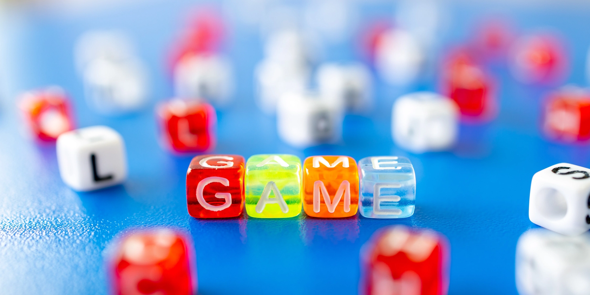 Dice with letters on showing the word GAME.
