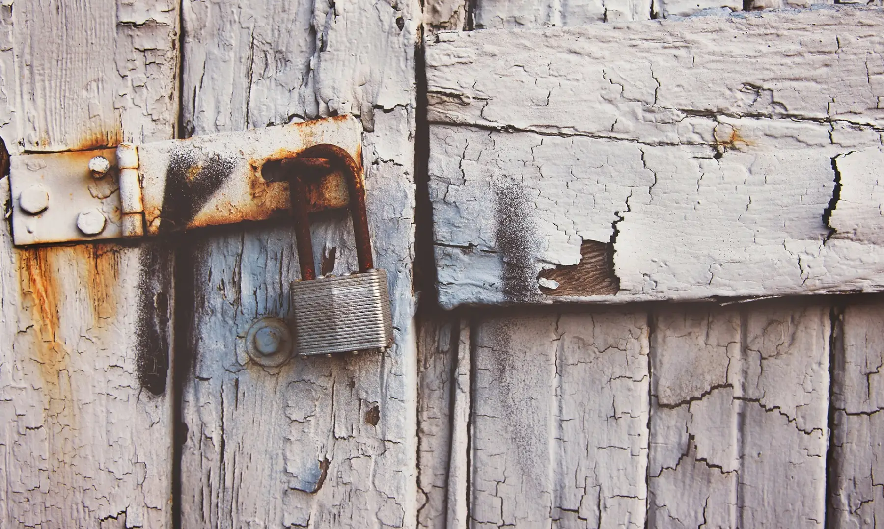 Padlock on old gate with flaky paint