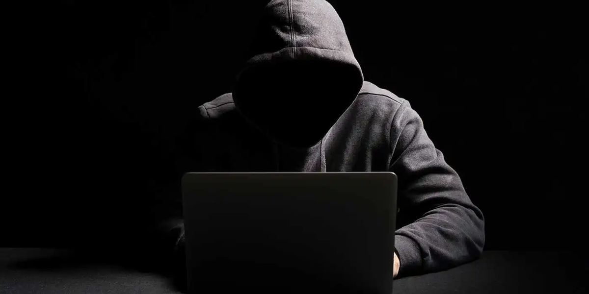 stereotypical image of a hacker working in a dark room at night not showing their face